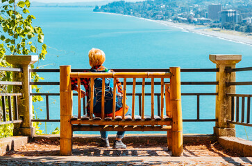 Lonely woman on a bamboo bench above the sea