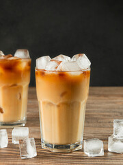 Two tall glasses close-up of cold coffee with milk on a wooden brown background.
