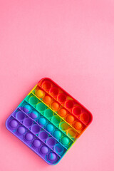 Anti-stress pop it a toy. Rainbow touch fidget spinner, on pink background. New fashion silicone toy. Vertical frame