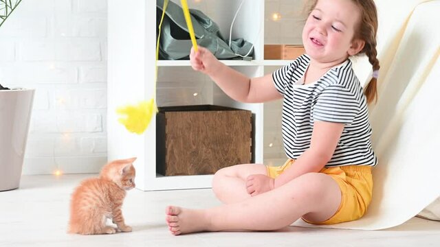 cute little ginger girl child playing with ginger funny kitten cat home. High quality photo