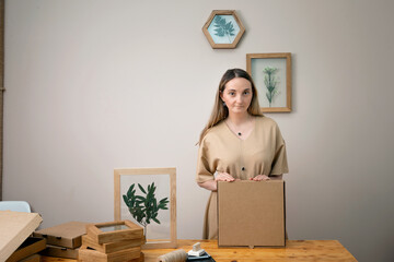 Fototapeta premium woman decorates Dry flowers in a frame. walls with botanical leaves. Eco-friendly boho decor. Real people personal space. 