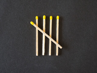 Matches with yellow heads representing the number five in the form of a tally marks, the fifth matchstick man crosses diagonally and forms a 