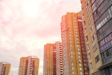 Fototapeta premium Dramatic red scenery of residential houses with street lanterns in front, evening sky with sun flare and distant spindrift clouds