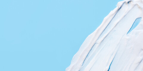 The texture of the skin or hair care product. White smears of cream, mask or balm on a blue background.