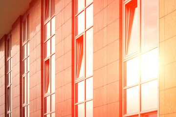 Modern building background with rows of glass windows. Sunlight is reflected.