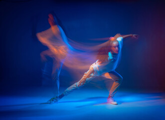 Mixed race female dancing in colorful neon light. Studio photo with long exposure. Expressive...