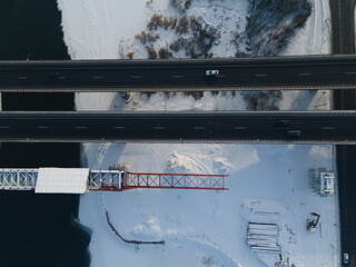 Aerial view of the bridge under construction over the river in winter with huge traffic. New bridge is being built next to the old one