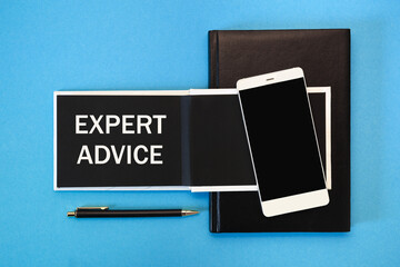 A white notebook with black pages, a smartphone and a pen on a blue background. The inscription EXPERT ADVICE