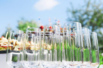 buffet in the open air - empty glasses on the background of cold snacks against the sky