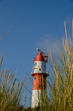 rot weisser Leuchtturm auf der Nordseeinsel Borkum mit Dünengras im Vordergrund
