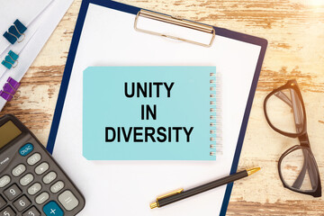 Notebook with text - Unity in Diversity near office supplies.