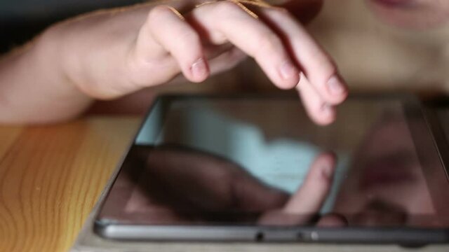 Close-up shot of a boy busy using tablet, selective focus with shallow depth of field.
