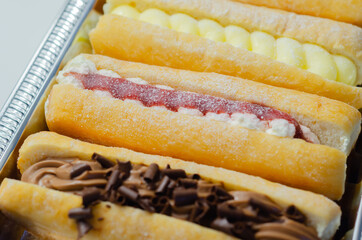 Mixed finger donuts filling chocolate, custard, jam and whipped cream, eclairs in different flavors