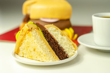 Piece of the Burger Cake, Madeira and chocolate sponge layered cake, filled with frosting covered with soft icing and edible sugar decorations