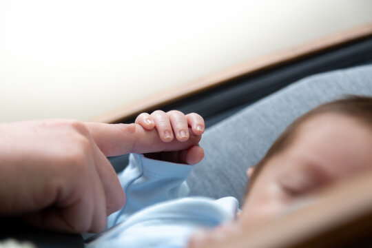 Peaceful and sleepy newborn baby, focus on the hand; family and love theme photography