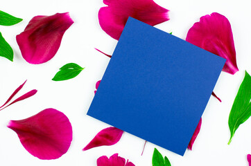 A clean sheet of blue colored paper mock up a greeting card. Sheet of paper on pink petals, concept for valentine's day, mother's day, birthday. View from above