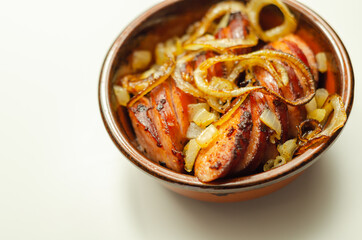 Traditionally roasted German sausage with onion served in a ceramic bowl