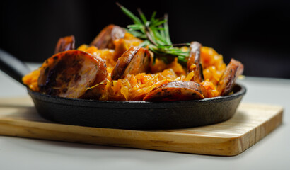 Traditional Polish dish called bigos made of sauerkraut, sausage and mushrooms, food served warm in a cast iron pan