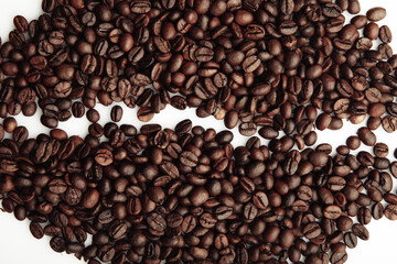 Roasted coffee beans laid out in the form of a large coffee grain close-up on a white background