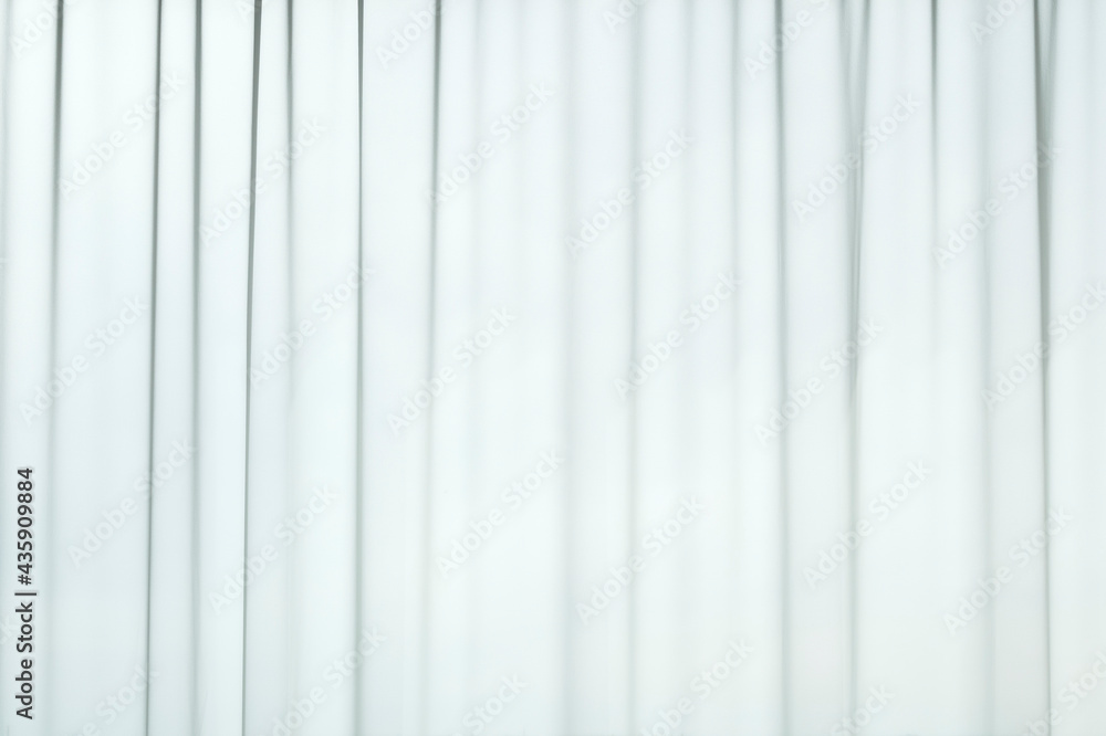 Poster light coming through a sheer, transparent and pleated white curtains or drapes. striped, vertical li