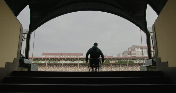 Unrecognizable sportsman riding wheelchair on stadium