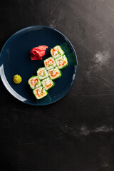 rolls in green rice paper in a blue plate on a black textured background