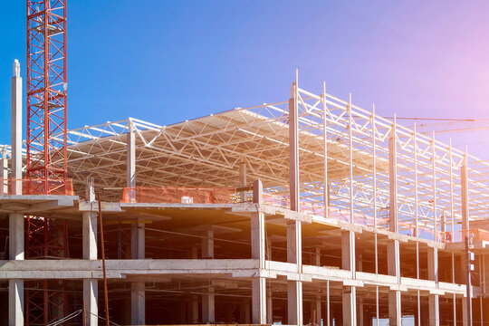 Closeup of Trade Center building during construction with steel frame shown against blue sky background. Retail shopping center under construction. Construction site where shopping mall is being built