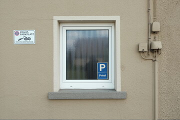 Hinweise für Parker und Falschparker im und neben dem Fenster in einer Fassade in Beige und...