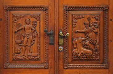 A detail of an old traditional wooden door on which is carved the figure of Poseidon and Mercury, in Trieste, Italy