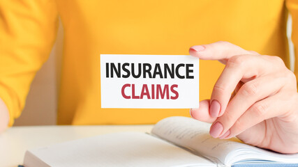 text insurance claims written on a white paper card in woman hand, concept