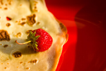 Ripe fresh strawberries on a thin pancake in a red plate, close-up.