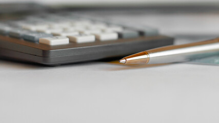 Close-up of silver pen and calculator on paper, defocus