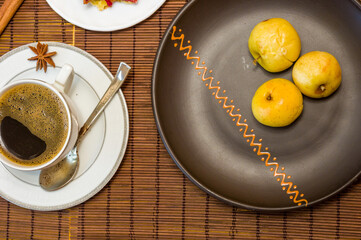 Still life - a hot cup of black coffee, homemade cookies with fruit, baked apples on a bamboo mat