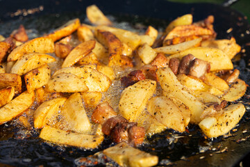Cooking fried potatoes in a large frying pan with natural seasoning
