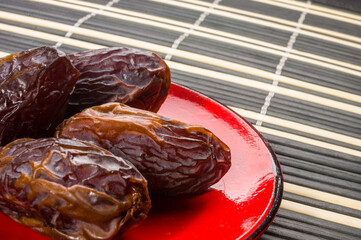 Big luxury dried date fruit in bowls on the bamboo mat, kurma ramadan kareem concept, close up.