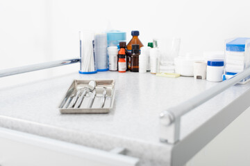 medicines and clean dental metal tools in tray on medical table.