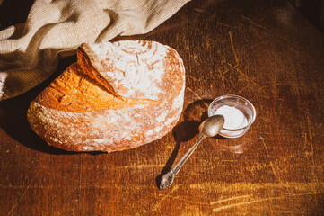 Still life - yeast-free buckwheat bread with coarse salt in glass jar, and a linen napkin on a wooden board, wooden background, hard light, photo in a low key.