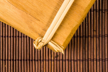 Chinese pressed PU-erh tea in bamboo leaf packaging on a bamboo Mat, close-up, macro