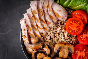 bowl of healthy quinoa with grilled chicken and vegetables on a dark rustic background