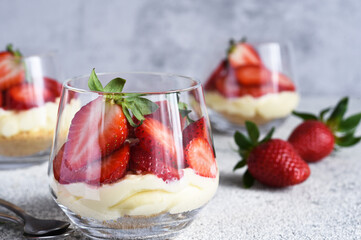 Cheesecake with strawberries in a glass on a light stone background. Dessert with strawberries.