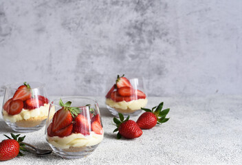 Cheesecake with strawberries in a glass on a light stone background. Dessert with strawberries.