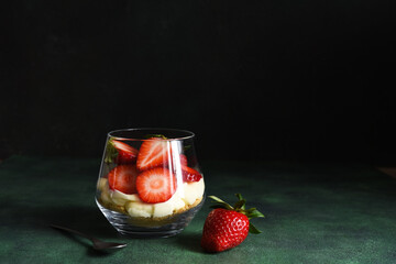 Tiramisu with strawberries in a glass on a dark stone background. Dessert with strawberries.