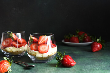 Tiramisu with strawberries in a glass on a dark stone background. Dessert with strawberries.