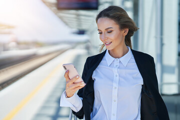 Elegant woman walking with bag and suitcase in the railway station