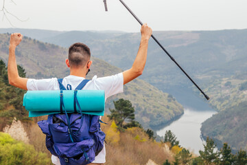 euphoric young man in the mountain with river landscape and arms raised