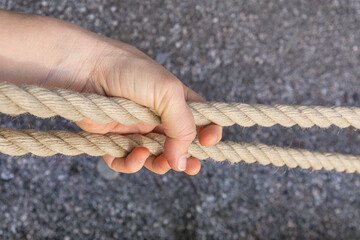 Girls hand holding two thick ropes