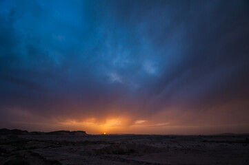 Colors of sunset with sun on horizon above landscape near Rissani in Morocco