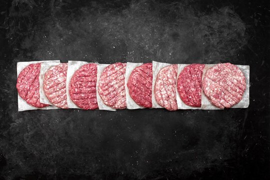 Raw Minced Steak Burgers from Beef and Pork Meat on Black Background, Overhead View. Raw Ground Beef, Round Patties for Cooking Homemade Burger On BBQ Grill, Top View