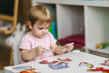 One and a half year old girl collects puzzles. Psychomotor skills and the development of logical thinking