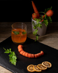 Composition of whole and wheeled carrots with sliced dried orange on slate plate and parsley leaves...